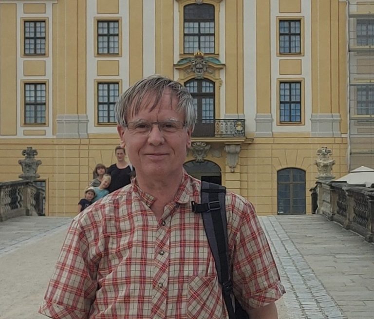 Andreas Bertram Auftragsgedicht über mich Andreas Bertram, Dichter, vor der gelblichen Fassade des Schlosses Moritzburg. Zufrieden lächelnd, angegrautes Haar, rotkariertes Hemd.